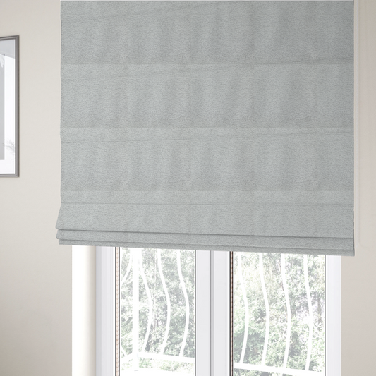 The fabric used to create these Roman blinds is a clean, contemporary light-grey and white weave. It is crafted with a dense, nubby construction that creates a subtle horizontal ribbing effect, providing both visual dimension and a soft, tactile quality.