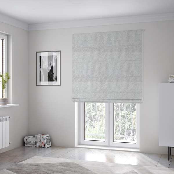 The fabric used to create these Roman blinds is a clean, contemporary light-grey and white weave. It is crafted with a dense, nubby construction that creates a subtle horizontal ribbing effect, providing both visual dimension and a soft, tactile quality.