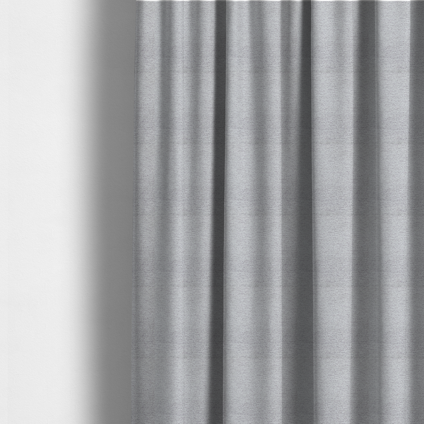 The fabric used to create these made-to-measure curtains is a refined, soft grey and white two-tone weave. It is crafted with a dense, nubby construction that creates a subtle horizontal ribbing effect, offering both visual dimension and a cosy, tactile quality.