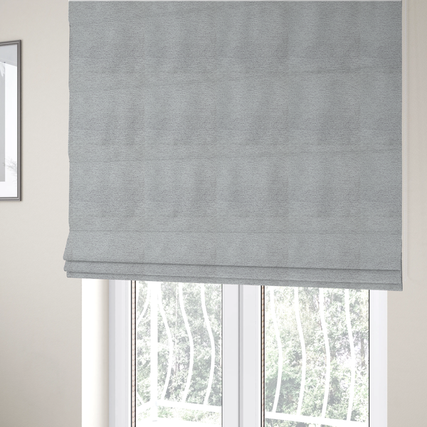 The fabric used to create these Roman blinds is a refined, soft grey and white two-tone weave. It is crafted with a dense, nubby construction that creates a subtle horizontal ribbing effect, offering both visual dimension and a cosy, tactile quality.