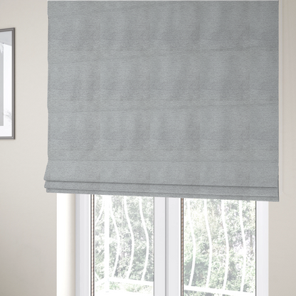 The fabric used to create these Roman blinds is a refined, soft grey and white two-tone weave. It is crafted with a dense, nubby construction that creates a subtle horizontal ribbing effect, offering both visual dimension and a cosy, tactile quality.