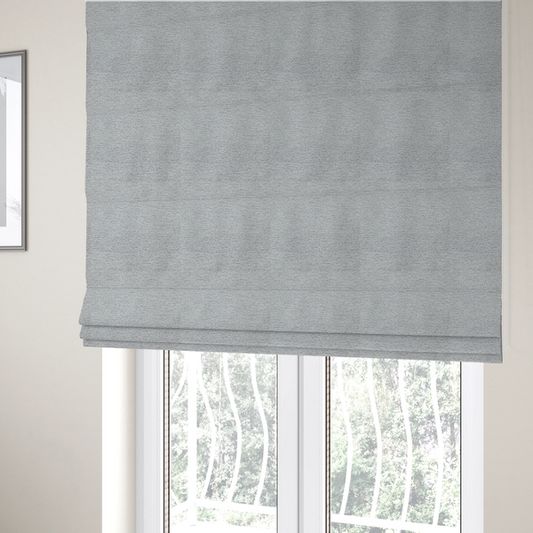 The fabric used to create these Roman blinds is a refined, soft grey and white two-tone weave. It is crafted with a dense, nubby construction that creates a subtle horizontal ribbing effect, offering both visual dimension and a cosy, tactile quality.