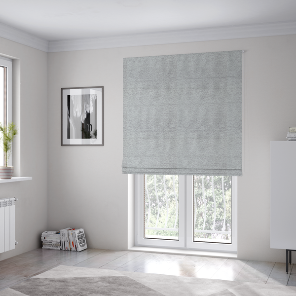 The fabric used to create these Roman blinds is a refined, soft grey and white two-tone weave. It is crafted with a dense, nubby construction that creates a subtle horizontal ribbing effect, offering both visual dimension and a cosy, tactile quality.