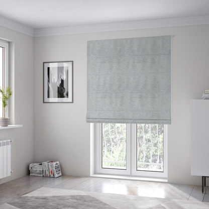 The fabric used to create these Roman blinds is a refined, soft grey and white two-tone weave. It is crafted with a dense, nubby construction that creates a subtle horizontal ribbing effect, offering both visual dimension and a cosy, tactile quality.