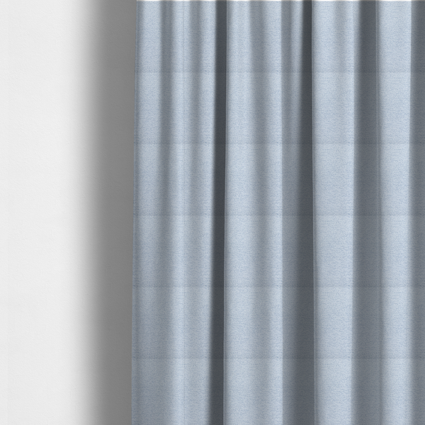 The fabric used to create these made-to-measure curtains is a serene, cool-toned light blue fabric featuring a dense, nubby weave that provides a subtle, calming texture, perfect for adding a touch of tranquil colour and refined style to home upholstery.