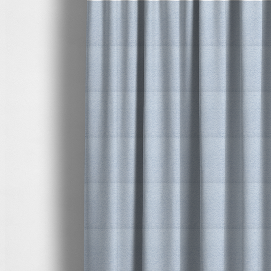 The fabric used to create these made-to-measure curtains is a serene, cool-toned light blue fabric featuring a dense, nubby weave that provides a subtle, calming texture, perfect for adding a touch of tranquil colour and refined style to home upholstery.