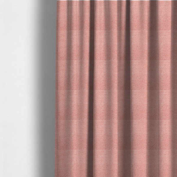The fabric used to create these made-to-measure curtains is a soft, pastel coral-pink fabric with a dense, nubby textured weave and subtle horizontal ribbing, adding a gentle and welcoming pop of colour to decorative cushions or accent pieces.
