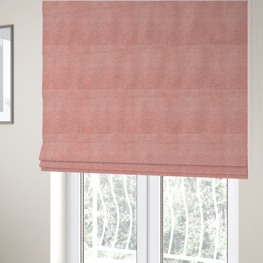 The fabric used to create these Roman blinds is a soft, pastel coral-pink fabric with a dense, nubby textured weave and subtle horizontal ribbing, adding a gentle and welcoming pop of colour to decorative cushions or accent pieces.