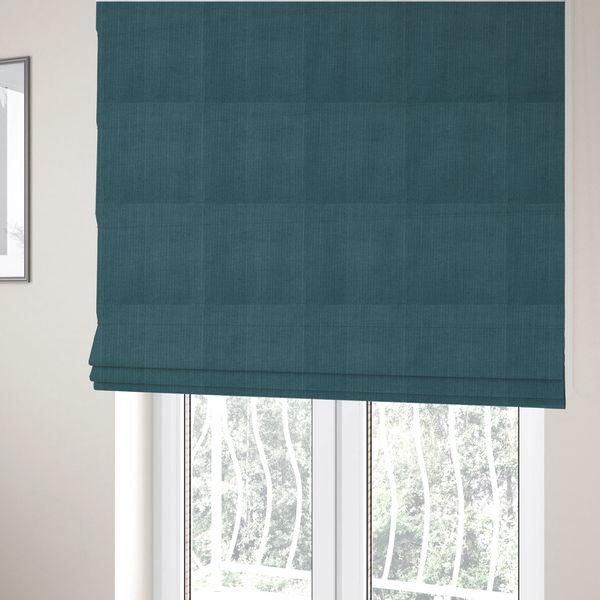 The fabric used to create these Roman blinds is a textured woven fabric in a dusty teal or muted slate blue colour.