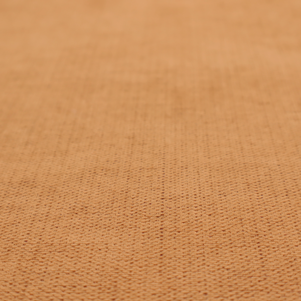 A textured woven fabric in a warm terracotta or soft pumpkin orange shade.