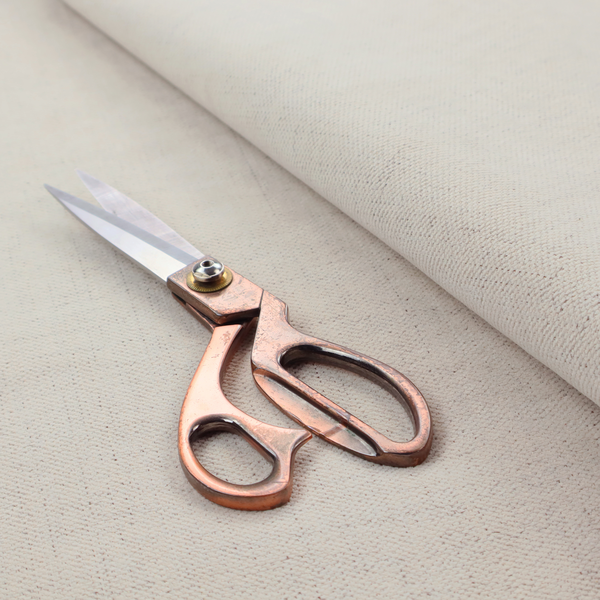 A textured woven fabric in a warm off-white, light cream, or pale beige shade.