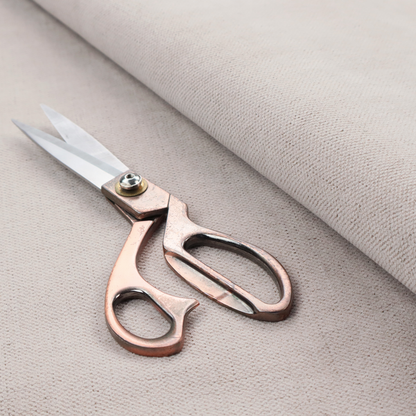 A textured woven fabric in a very pale, dusty blush pink or soft ivory shade with a subtle rosy undertone.