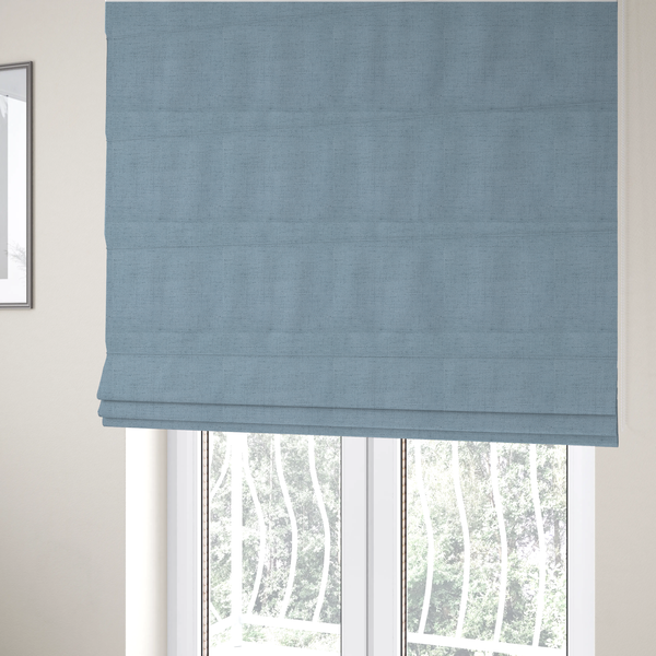 The fabric used to create these Roman blinds is a textured woven fabric in a soft, light powder blue or serene sky blue shade.