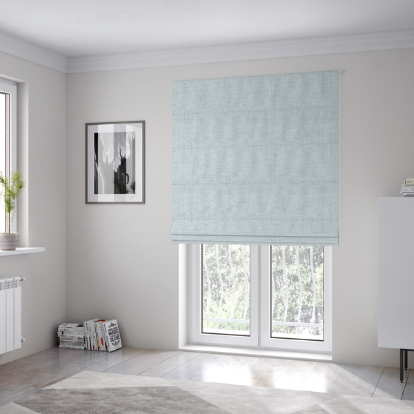 The fabric used to create these Roman blinds is a textured woven fabric in a very pale, icy blue or light mist grey-blue shade.