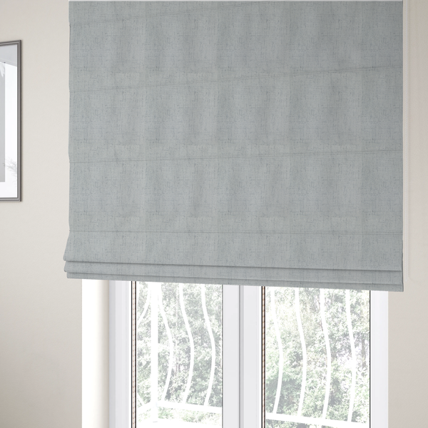 The fabric used to create these Roman blinds is a textured woven fabric in a cool, light grey or soft slate shade.