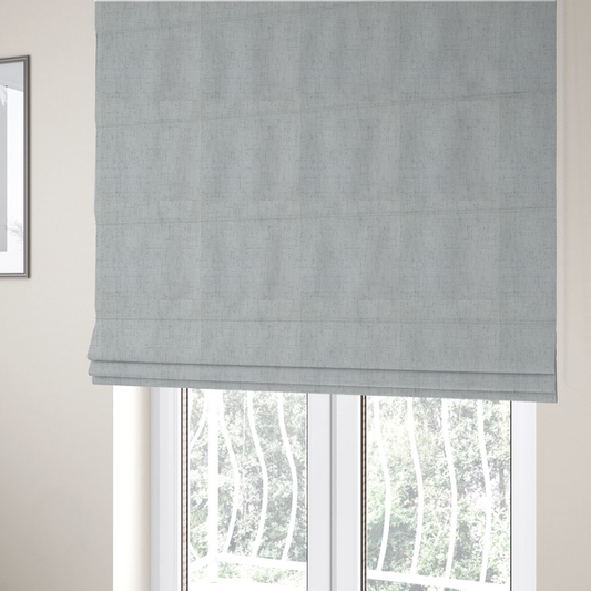 The fabric used to create these Roman blinds is a textured woven fabric in a cool, light grey or soft slate shade.