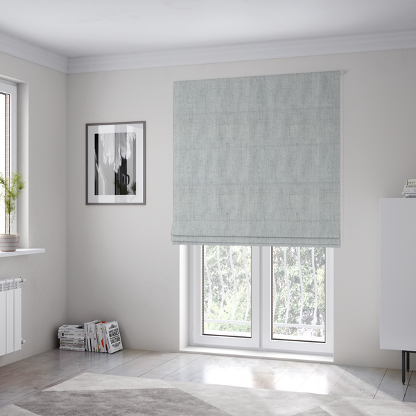 The fabric used to create these Roman blinds is a textured woven fabric in a cool, light grey or soft slate shade.