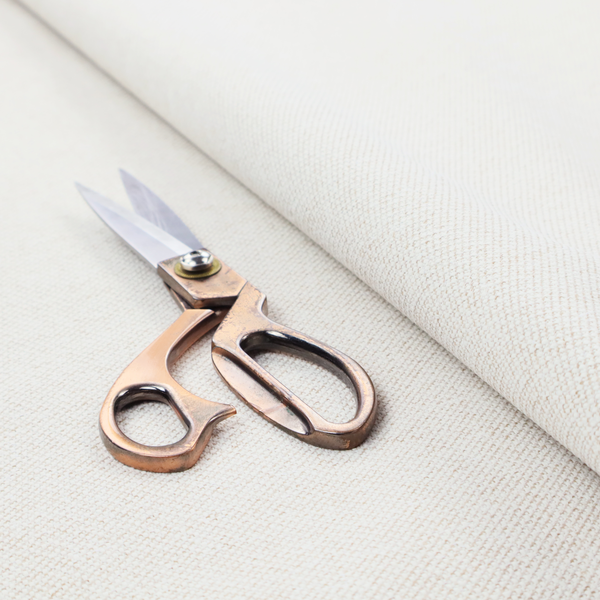 A cream or ivory woven upholstery fabric with a fine, pebble-like texture.