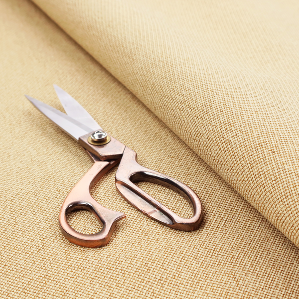 A sandy beige textile featuring a tight diagonal twill weave. The fabric is composed of interlaced cream and light tan threads, creating a fine, granular texture with a matte finish.