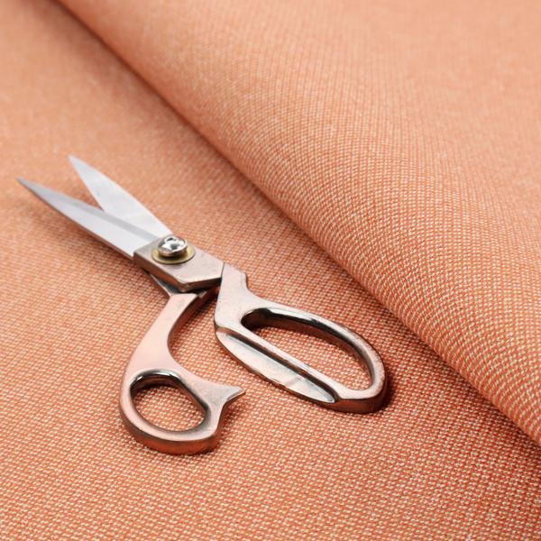 A vibrant apricot or orange textile with a tight diagonal twill weave. The fabric is woven with a primary saturated orange thread interspersed with fine white or cream yarns, creating a bright, textured surface with a subtle "salt and pepper" effect.