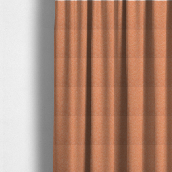 The fabric used to create these made-to-measure curtains is a vibrant apricot or orange textile with a tight diagonal twill weave. The fabric is woven with a primary saturated orange thread interspersed with fine white or cream yarns, creating a bright, textured surface with a subtle "salt and pepper" effect.