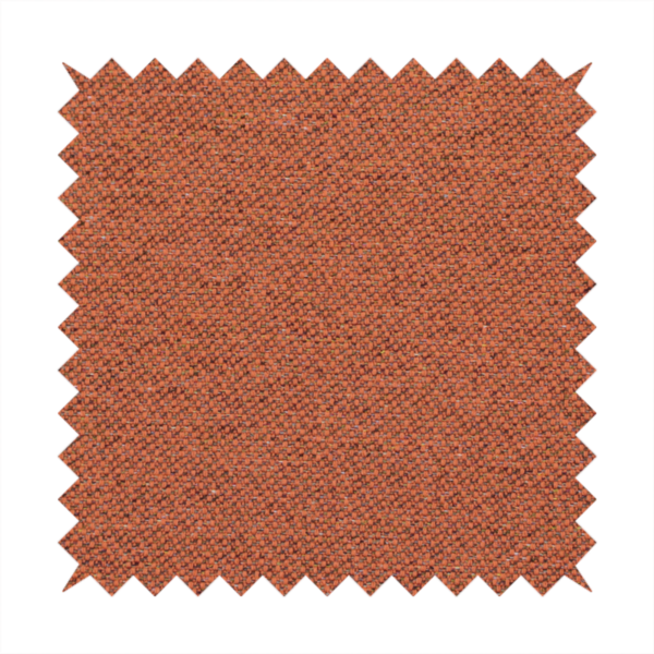 A deep rust or burnt orange textile with a dense diagonal twill weave. The fabric features a rich, multi-tonal blend of saturated orange yarns interlaced with darker brown and subtle flecks of green or gold, giving it a heathered, earthy depth.