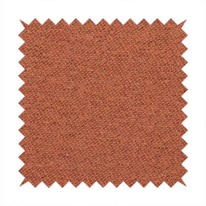 A deep rust or burnt orange textile with a dense diagonal twill weave. The fabric features a rich, multi-tonal blend of saturated orange yarns interlaced with darker brown and subtle flecks of green or gold, giving it a heathered, earthy depth.