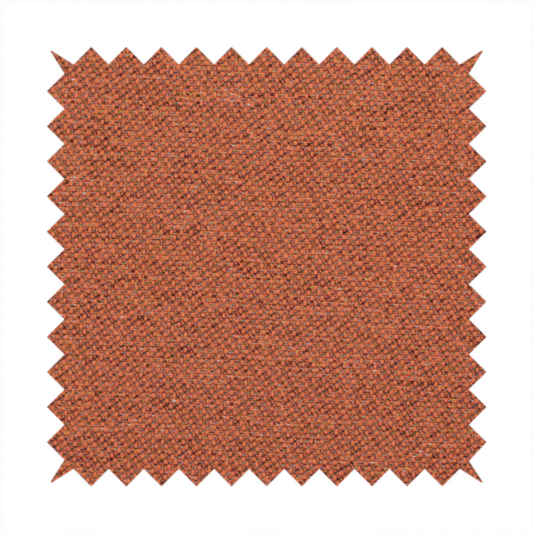 A deep rust or burnt orange textile with a dense diagonal twill weave. The fabric features a rich, multi-tonal blend of saturated orange yarns interlaced with darker brown and subtle flecks of green or gold, giving it a heathered, earthy depth.