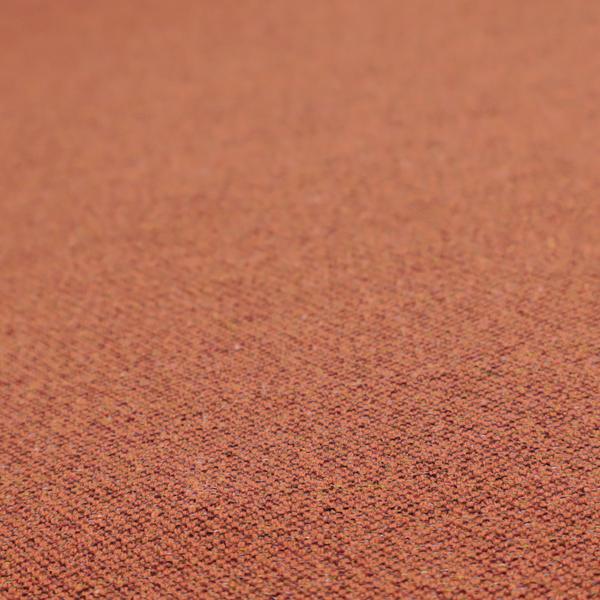A deep rust or burnt orange textile with a dense diagonal twill weave. The fabric features a rich, multi-tonal blend of saturated orange yarns interlaced with darker brown and subtle flecks of green or gold, giving it a heathered, earthy depth.