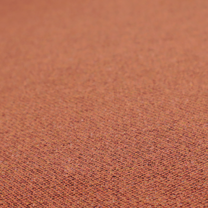 A deep rust or burnt orange textile with a dense diagonal twill weave. The fabric features a rich, multi-tonal blend of saturated orange yarns interlaced with darker brown and subtle flecks of green or gold, giving it a heathered, earthy depth.