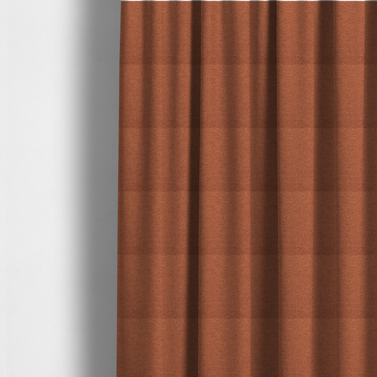 The fabric used to create these made-to-measure curtains is a deep rust or burnt orange textile with a dense diagonal twill weave. The fabric features a rich, multi-tonal blend of saturated orange yarns interlaced with darker brown and subtle flecks of green or gold, giving it a heathered, earthy depth.