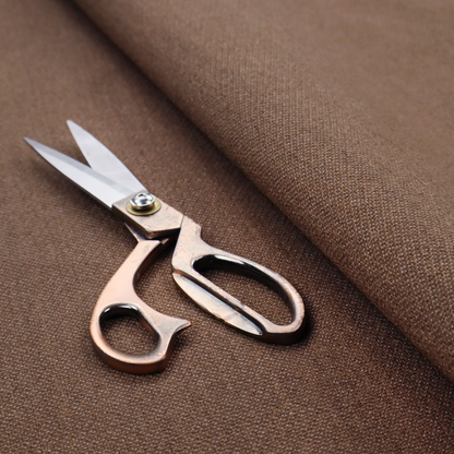 a dark chocolate or mocha brown textile with a tight diagonal twill weave. The fabric is woven with a deep brown base interspersed with fine, lighter threads that create a subtle shimmering or "salt and pepper" effect across the surface.