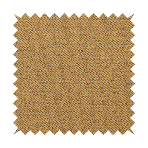 A golden mustard or ochre textile featuring a dense diagonal twill weave. The fabric is a multi-tonal blend, interlacing warm yellow-gold yarns with subtle flecks of darker brown and charcoal, creating a rich, heathered depth.