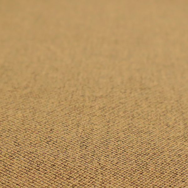 A golden mustard or ochre textile featuring a dense diagonal twill weave. The fabric is a multi-tonal blend, interlacing warm yellow-gold yarns with subtle flecks of darker brown and charcoal, creating a rich, heathered depth.