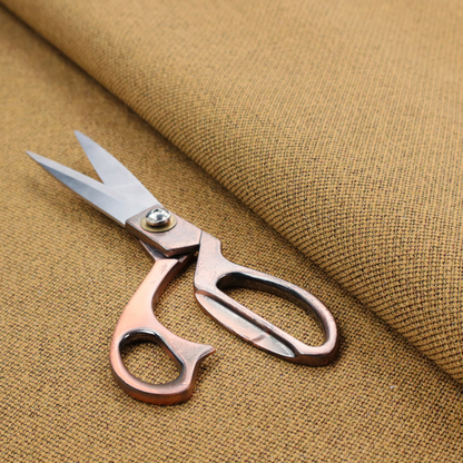 A golden mustard or ochre textile featuring a dense diagonal twill weave. The fabric is a multi-tonal blend, interlacing warm yellow-gold yarns with subtle flecks of darker brown and charcoal, creating a rich, heathered depth.