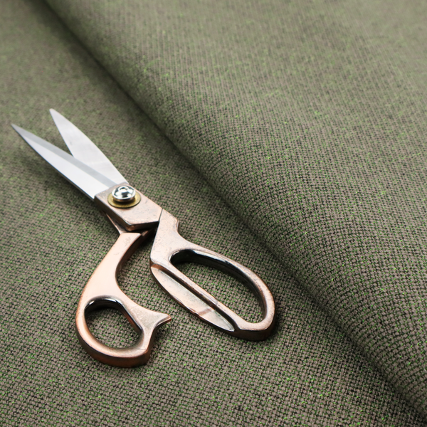 An olive or moss green textile featuring a dense diagonal twill weave. The fabric is a multi-tonal blend, interlacing earthy brownish-grey yarns with vibrant lime green flecks, creating a textured, heathered appearance.