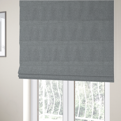 The fabric used to create these Roman blinds is a cool steel or light blue-grey textile featuring a tight diagonal twill weave. The fabric is a multi-tonal blend, interlacing medium grey yarns with pale blue and crisp white threads, creating a clean, heathered appearance.