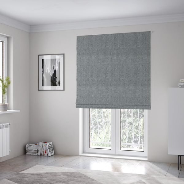 The fabric used to create these Roman blinds is a cool steel or light blue-grey textile featuring a tight diagonal twill weave. The fabric is a multi-tonal blend, interlacing medium grey yarns with pale blue and crisp white threads, creating a clean, heathered appearance.