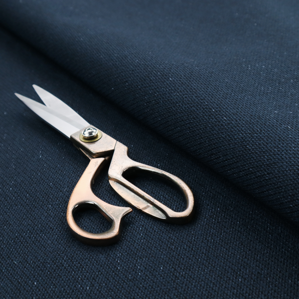 A deep navy or midnight blue textile featuring a tight diagonal twill weave. The fabric is woven primarily with saturated dark blue yarns, interspersed with very fine, sparse white or light grey flecks that create a subtle starlight effect.