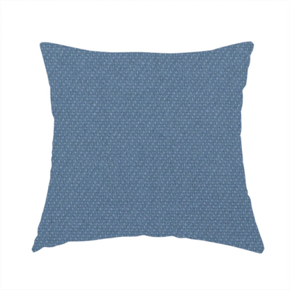 The fabric used to create this handmade cushion is a medium denim or cornflower blue textile featuring a tight diagonal twill weave. The fabric is woven with a blend of soft blue and muted grey-blue yarns, creating a calm, uniform colour profile with subtle tonal depth.