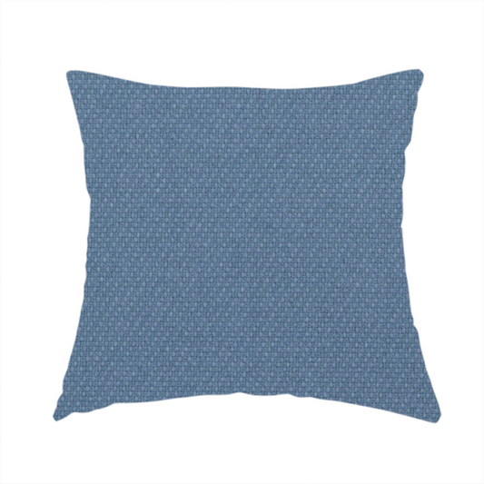 The fabric used to create this handmade cushion is a medium denim or cornflower blue textile featuring a tight diagonal twill weave. The fabric is woven with a blend of soft blue and muted grey-blue yarns, creating a calm, uniform colour profile with subtle tonal depth.