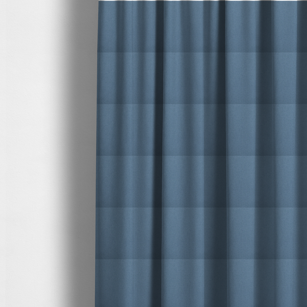 The fabric used to create these made-to-measure curtains is a medium denim or cornflower blue textile featuring a tight diagonal twill weave. The fabric is woven with a blend of soft blue and muted grey-blue yarns, creating a calm, uniform colour profile with subtle tonal depth.