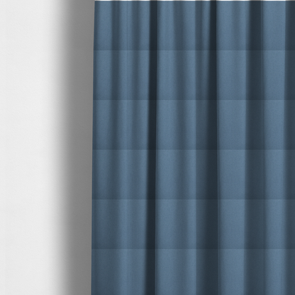 The fabric used to create these made-to-measure curtains is a medium denim or cornflower blue textile featuring a tight diagonal twill weave. The fabric is woven with a blend of soft blue and muted grey-blue yarns, creating a calm, uniform colour profile with subtle tonal depth.