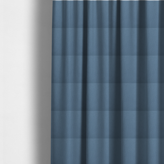 The fabric used to create these made-to-measure curtains is a medium denim or cornflower blue textile featuring a tight diagonal twill weave. The fabric is woven with a blend of soft blue and muted grey-blue yarns, creating a calm, uniform colour profile with subtle tonal depth.