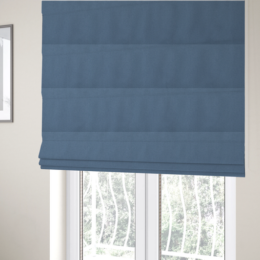The fabric used to create these Roman blinds is a medium denim or cornflower blue textile featuring a tight diagonal twill weave. The fabric is woven with a blend of soft blue and muted grey-blue yarns, creating a calm, uniform colour profile with subtle tonal depth.