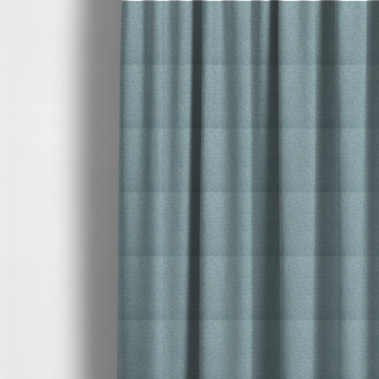 The fabric used to create these made-to-measure curtains is a dusty aqua or pale teal textile featuring a tight diagonal twill weave. The fabric is a multi-tonal blend, interlacing soft blue-green yarns with subtle flecks of grey and pale gold, creating a sophisticated, heathered depth.