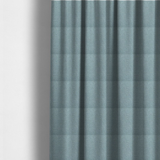 The fabric used to create these made-to-measure curtains is a dusty aqua or pale teal textile featuring a tight diagonal twill weave. The fabric is a multi-tonal blend, interlacing soft blue-green yarns with subtle flecks of grey and pale gold, creating a sophisticated, heathered depth.