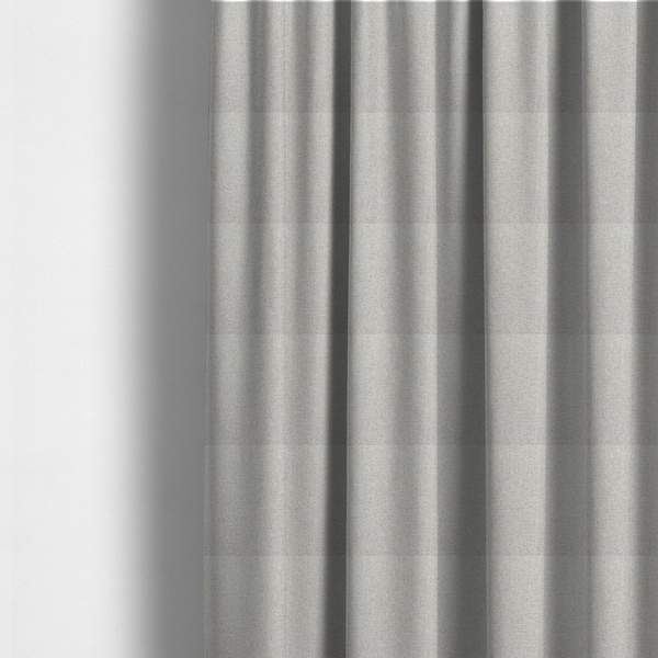 The fabric used to create these made-to-measure curtains is a light oatmeal or pearl grey textile featuring a tight diagonal twill weave. The fabric is a multi-tonal blend, interlacing crisp white and pale grey yarns with subtle flecks of soft gold and charcoal, creating a luminous, heathered appearance.