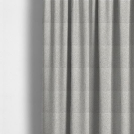 The fabric used to create these made-to-measure curtains is a light oatmeal or pearl grey textile featuring a tight diagonal twill weave. The fabric is a multi-tonal blend, interlacing crisp white and pale grey yarns with subtle flecks of soft gold and charcoal, creating a luminous, heathered appearance.