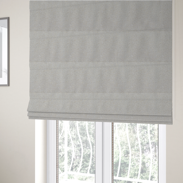 The fabric used to create these Roman blinds is a light oatmeal or pearl grey textile featuring a tight diagonal twill weave. The fabric is a multi-tonal blend, interlacing crisp white and pale grey yarns with subtle flecks of soft gold and charcoal, creating a luminous, heathered appearance.